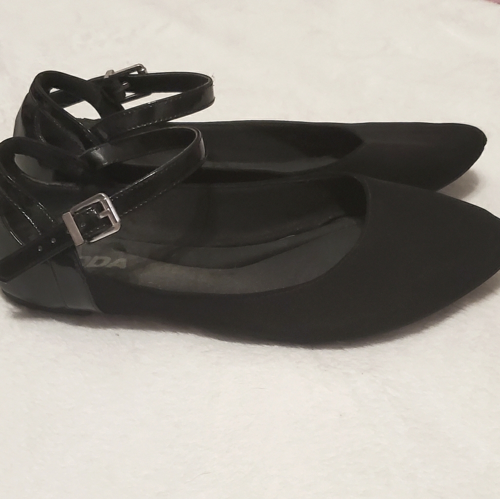 A pair of black flats with an ankle strap